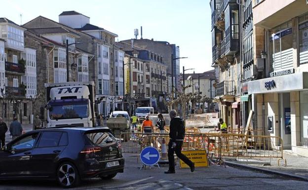 Unos vecinos cruzan por la zona vallada de la avenida, donde los obreros avanzan en los trabajos. 