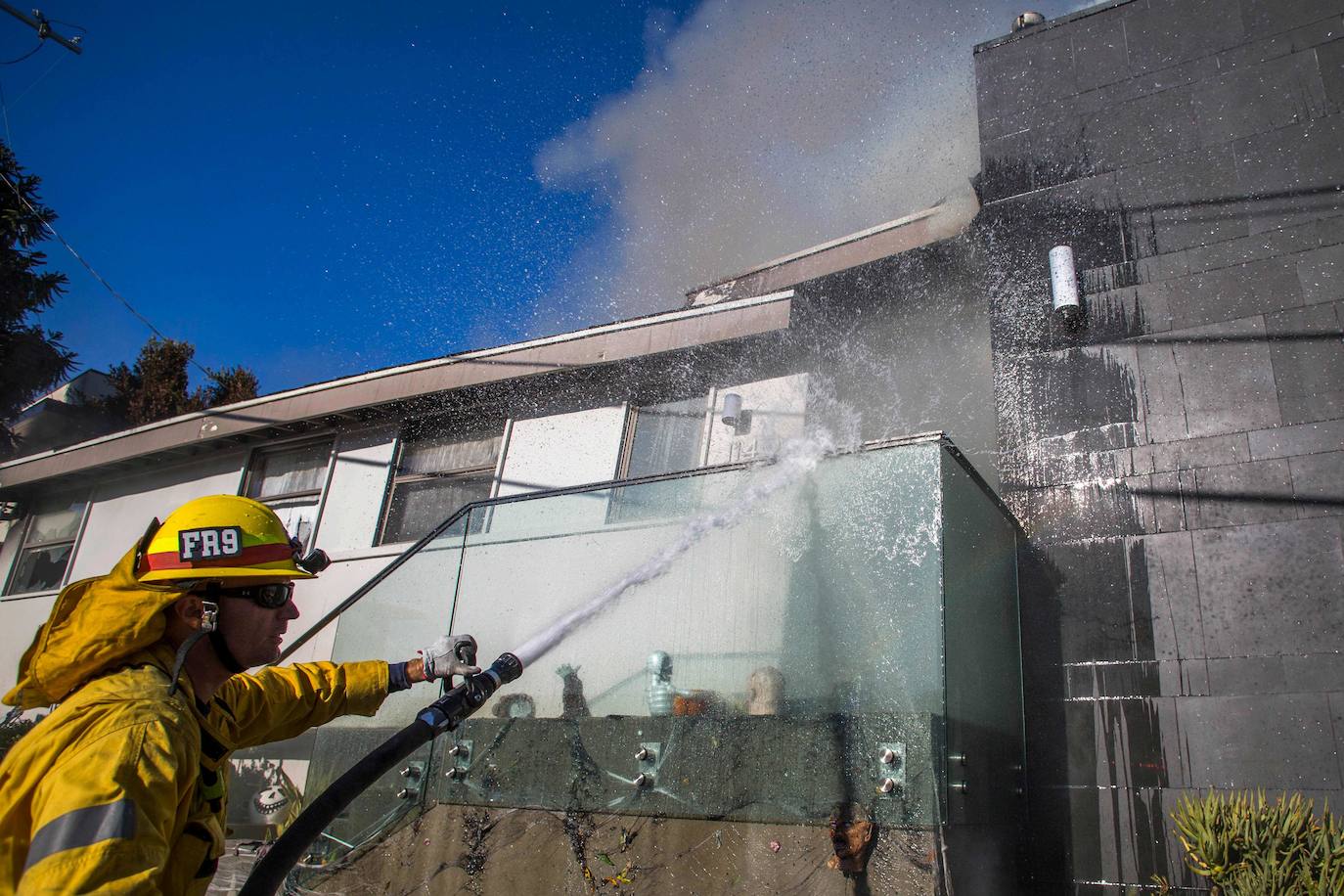 Un bombero arroja agua sobre una casa durante el 'Getty Fire'