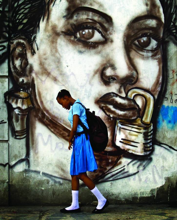 Una alumna de un colegio femenino de Puerto Príncipe pasa delante de un mural que denuncia la opresión de la mujer haitiana; este es uno de los 140 países donde el aborto está restringido por ley