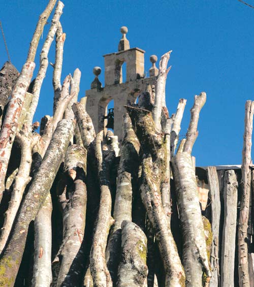 Montón de leña con la espadaña al fondo.