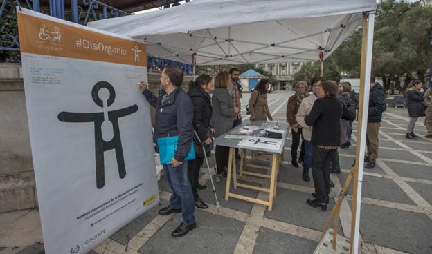 Un hombre firma el mural con el símbolo que representará a la discapacidad orgánica.