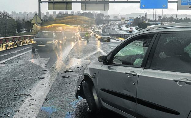 Un coche aguarda a las asistencias después de sufrir un accidente de tráfico en una jornada lluviosa. 