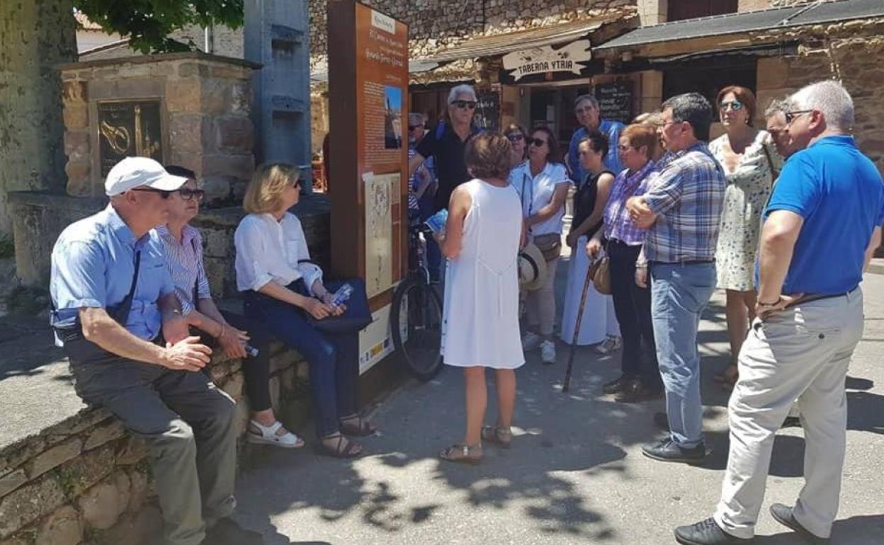 Visitantes ante uno de los paneles de la ruta literaria que recorre los distintos lugares de Molledo en los que Delibes desarrolla la novela 'El Camino'