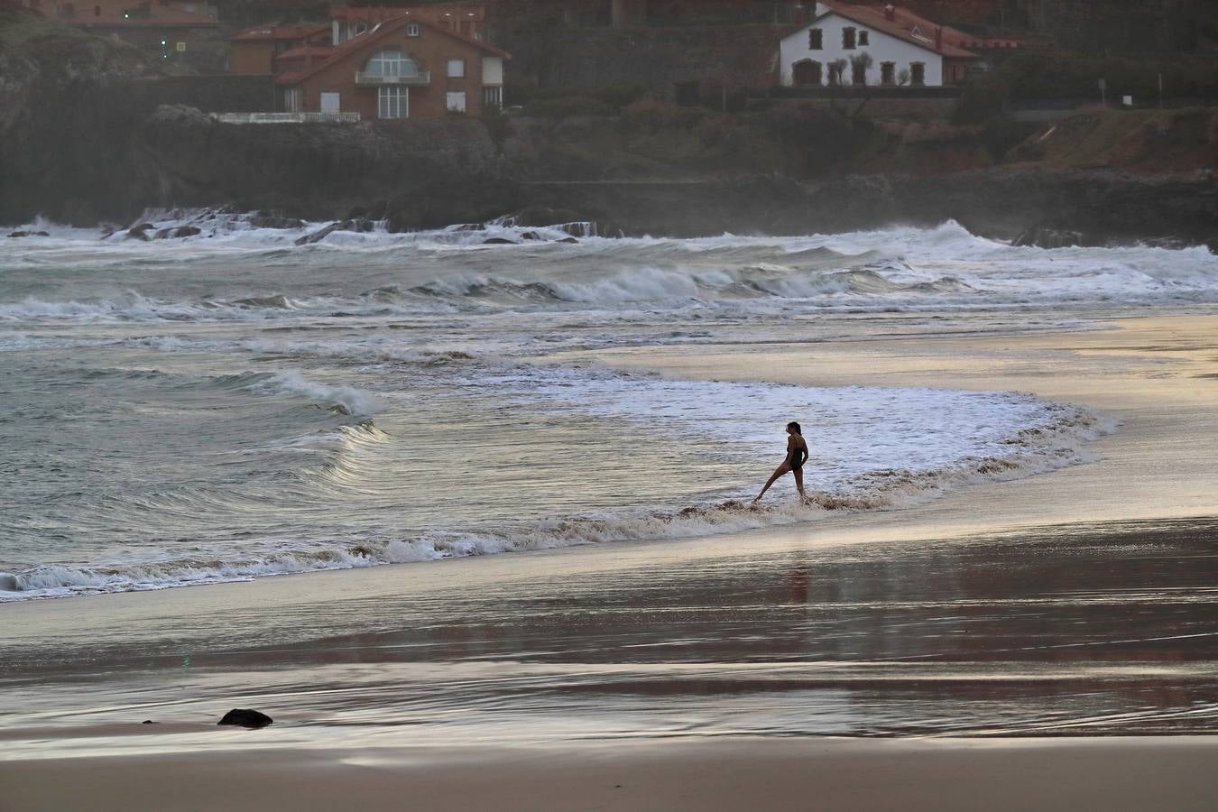 Una joven desafía el mal tiempo en la playa de Comillas.