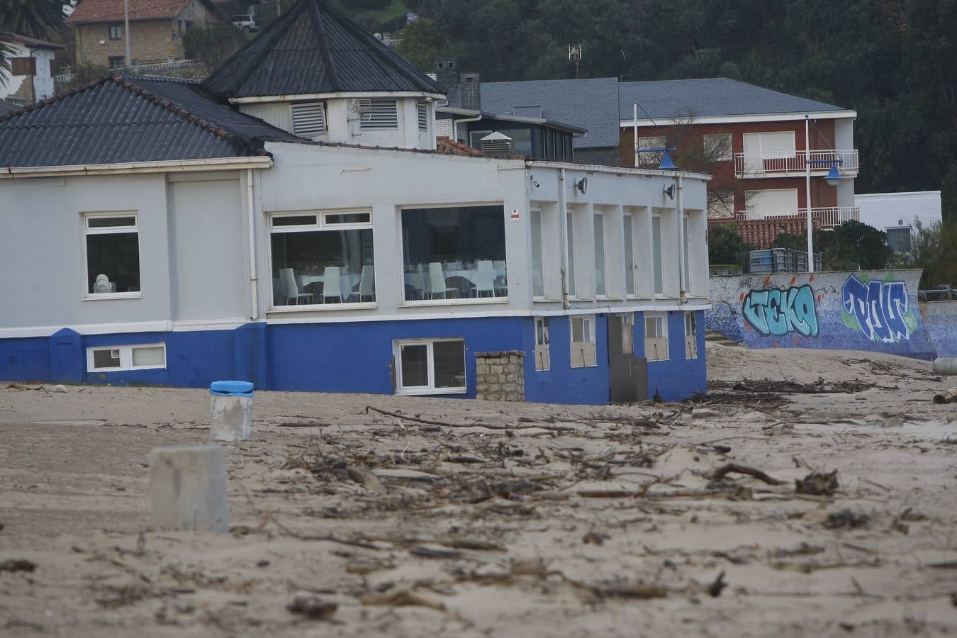 Un restaurante en la Playa de La Concha en Suances, rodeado de ramas arrastradas por la marea y con más arena de lo habitual.