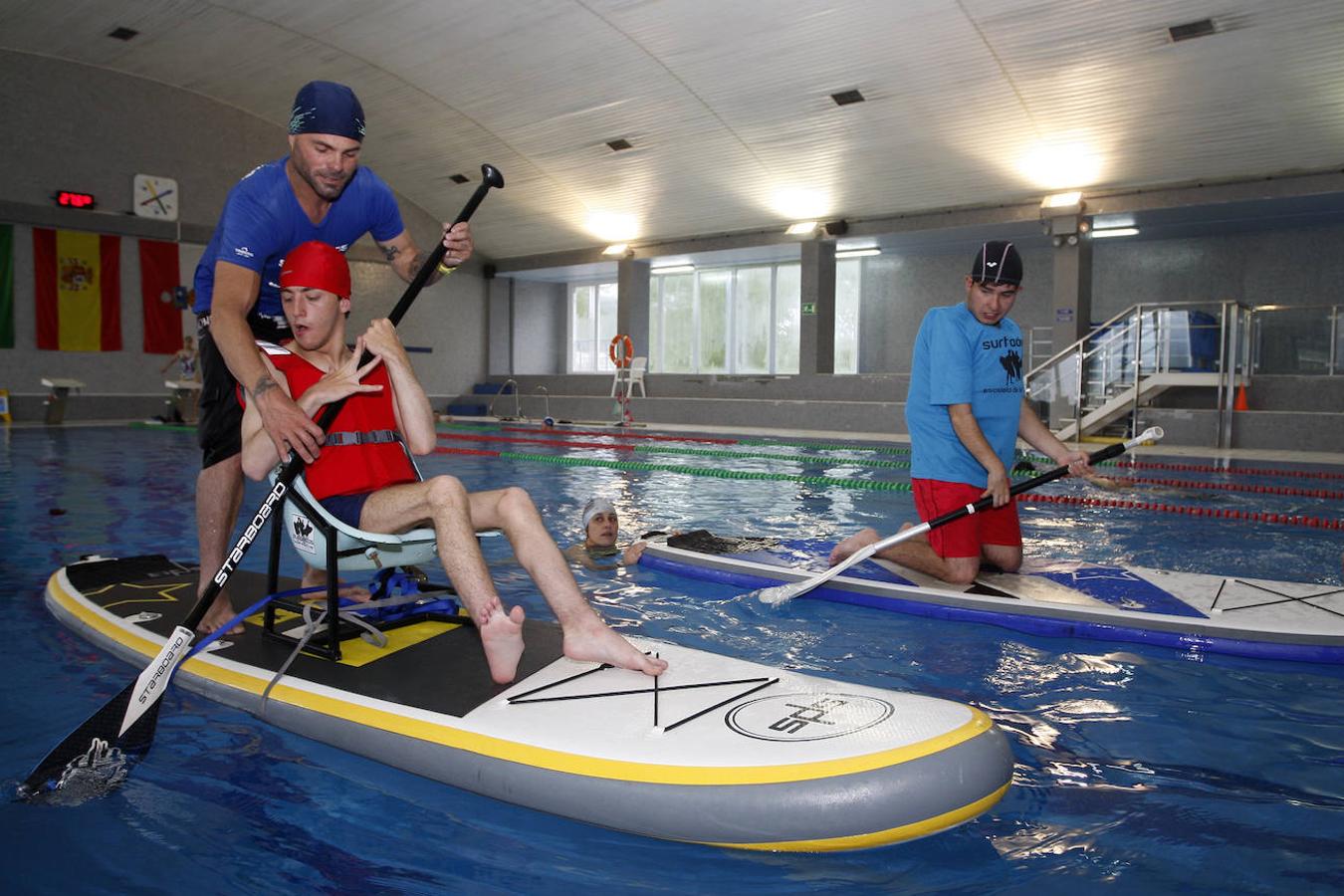 Alumnos del centro de educación especial Fernando Arce de Torrelavega realizan prácticas de paddle surf en la piscina municipal de La Lechera de la mano del profesor Sergio García.