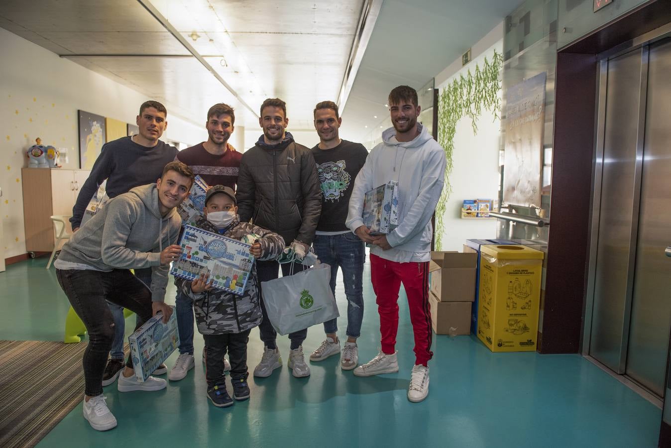 Un niño pequeño sostiene los regalos junto a Buñuel, Sergio Ruiz, Moi, David Rodríguez y Luca Zidane (de izquierda a derecha).