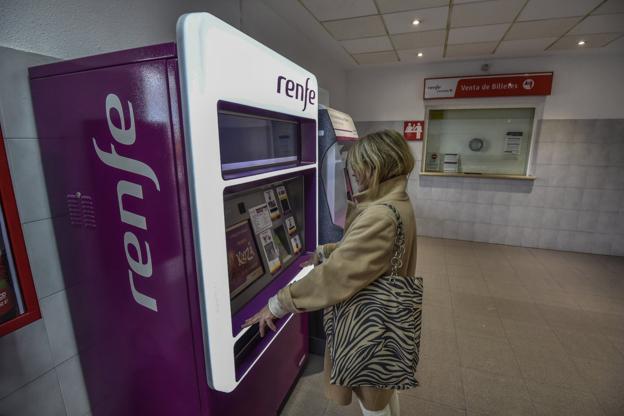 Una mujer utiliza una máquina autoventa para adquirir un billete de tren porque la ventanilla presencial ya no está operativa.