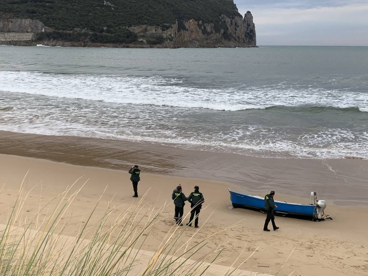 Guardias civiles, al lado de la barca de los náufragos varada en la playa Salvé.