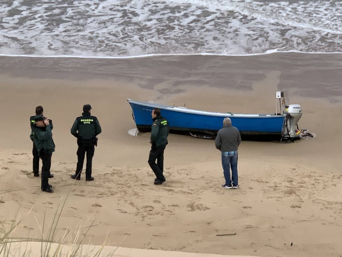 Guardias civiles, al lado de la barca de los náufragos varada en la playa Salvé.