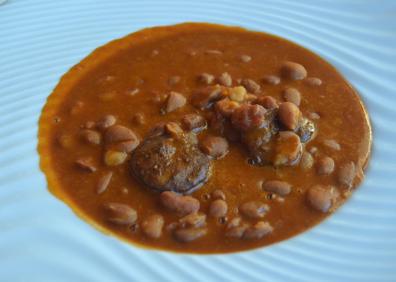 Imagen secundaria 1 - Arriba, el aperitivo en el exterior, rabas y vermut. Abajo, alubias rojas de olla ferroviaria y milhojas de berenjena y bacalao.