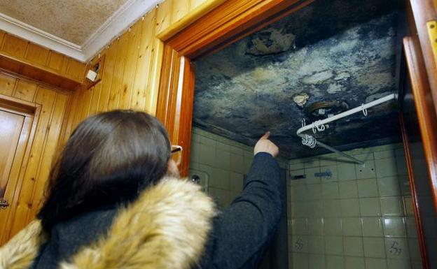 Una vecina muestra las manchas de humedad que hay en un baño de la vivienda.