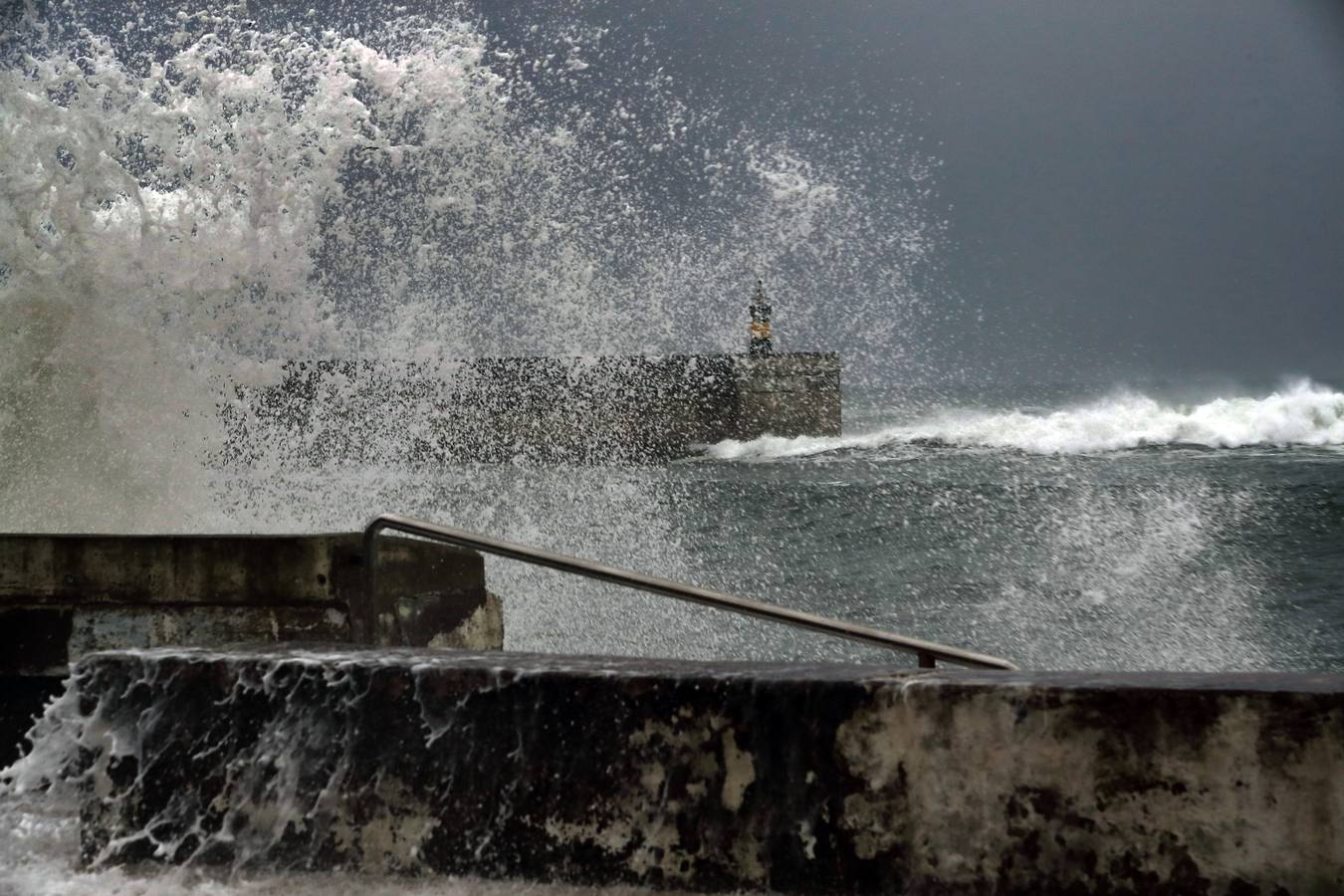 Las olas saltan por encima del espigón del puerto de Comillas