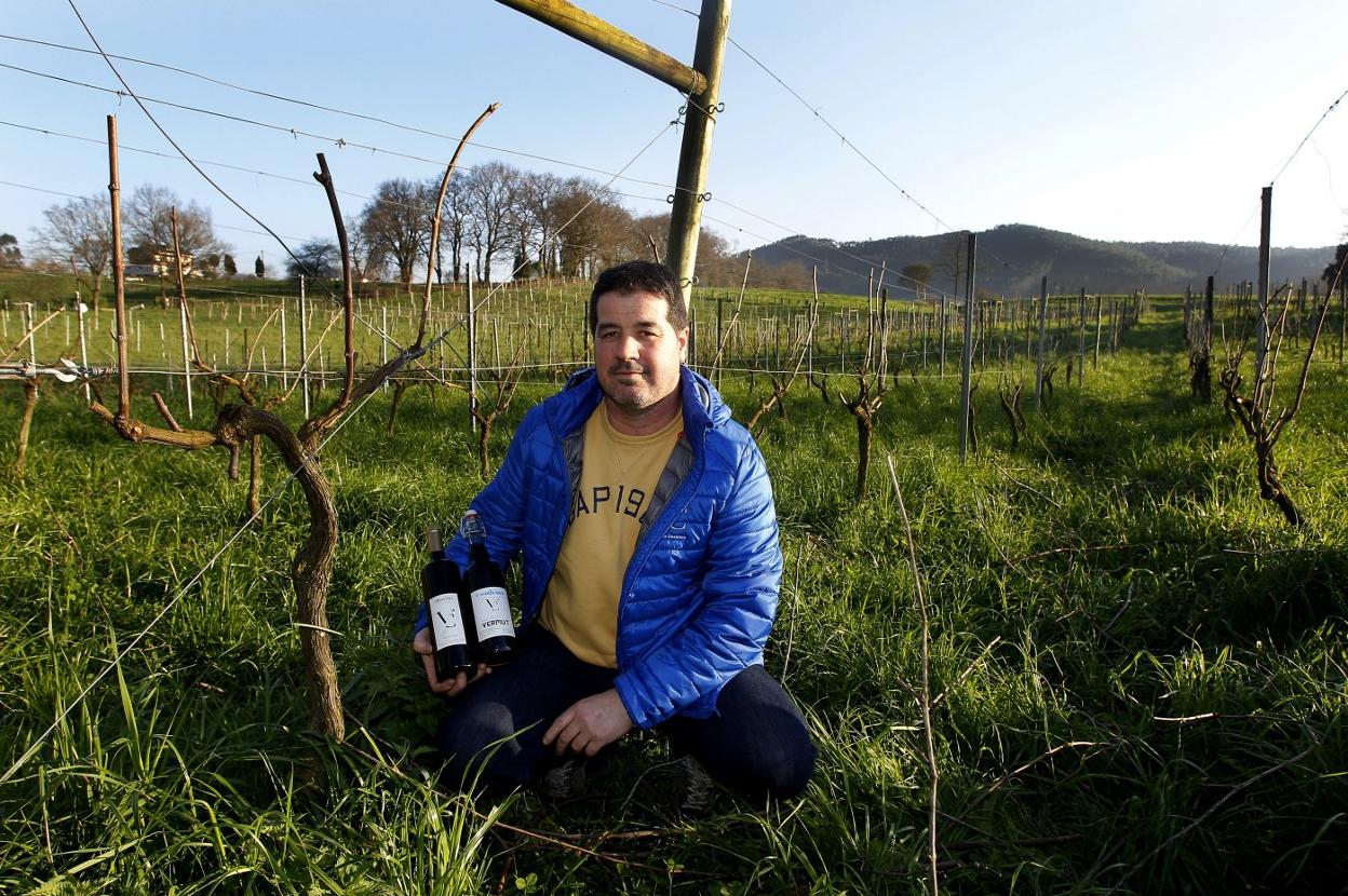 El viticultor, junto a las viñas y con dos botellas del vino que elabora en Vargas. 