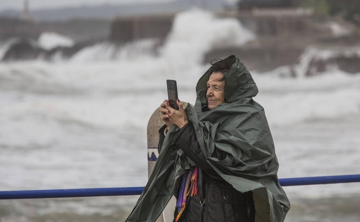 Una mujer toma fotografías en la playa de El Camello, en un día de temporal.