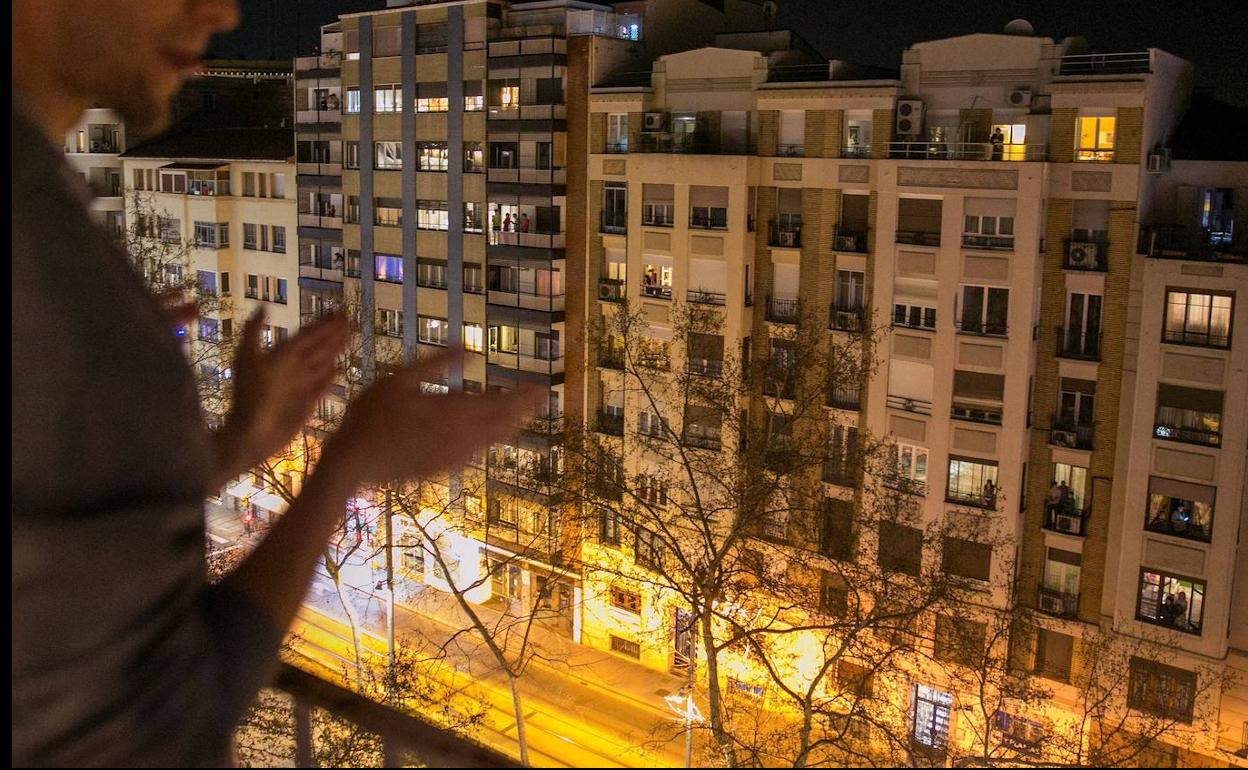 Un ciudadano se une al aplauso colectivo desde la ventana de su casa.