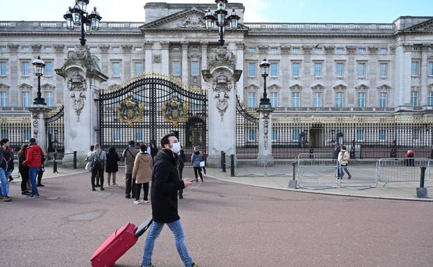 Un hombre con mascarilla pasea frente al Palacio de Buckingham donde se han reunido menos personas de lo habitual