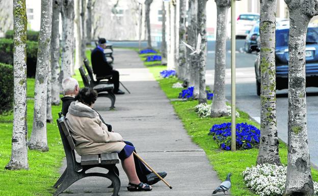 Personas mayores sentadas en bancos de la avenida de Andalucía.