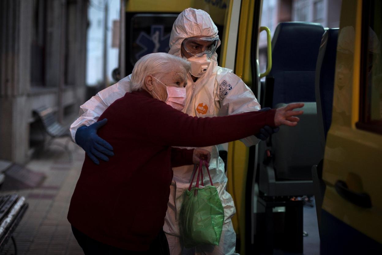 Un trabajador sanitario ayuda a trasladar de residencia, en Orense, a personas mayores que han dado positivo. 