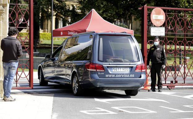 Un coche fúnebre entra a un cementerio.