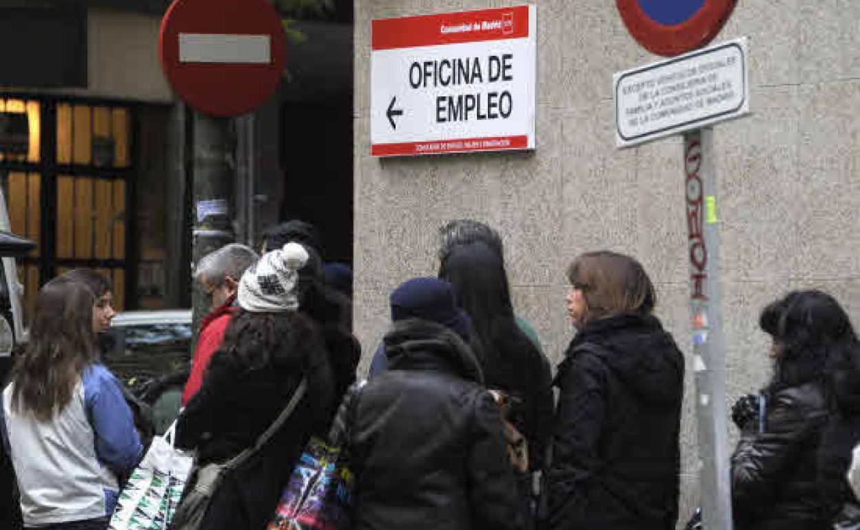 Un grupo de parados hacen cola a las puertas de una oficina de empleo.