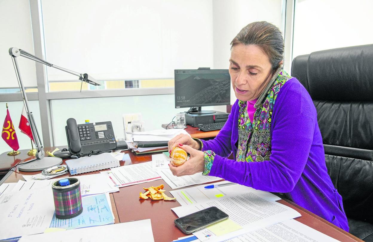 La consejera de Presidencia y Justicia, Paula Fernández Viaña, pela una mandarina mientras atiende una llamada en su despacho.