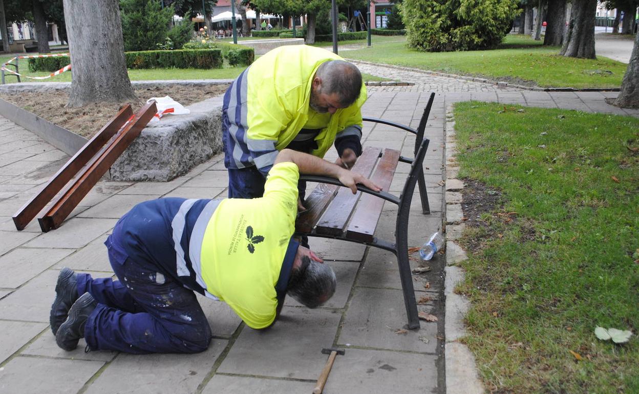 Trabajadores contratados por el programa de Corporaciones Locales colocan un banco en el Parque de Cupido de Reinosa.