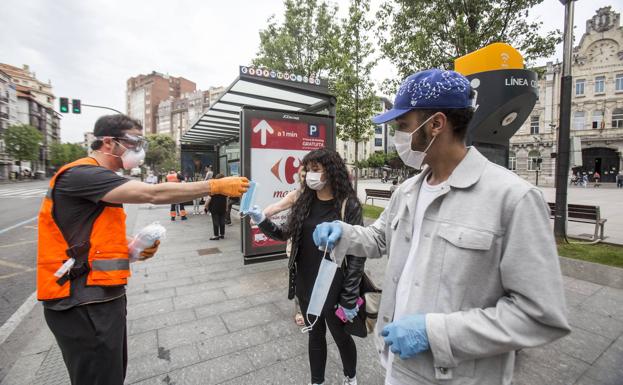 Reparto de mascarillas en la parada de autobús de la plaza del Ayuntamiento de Santander.