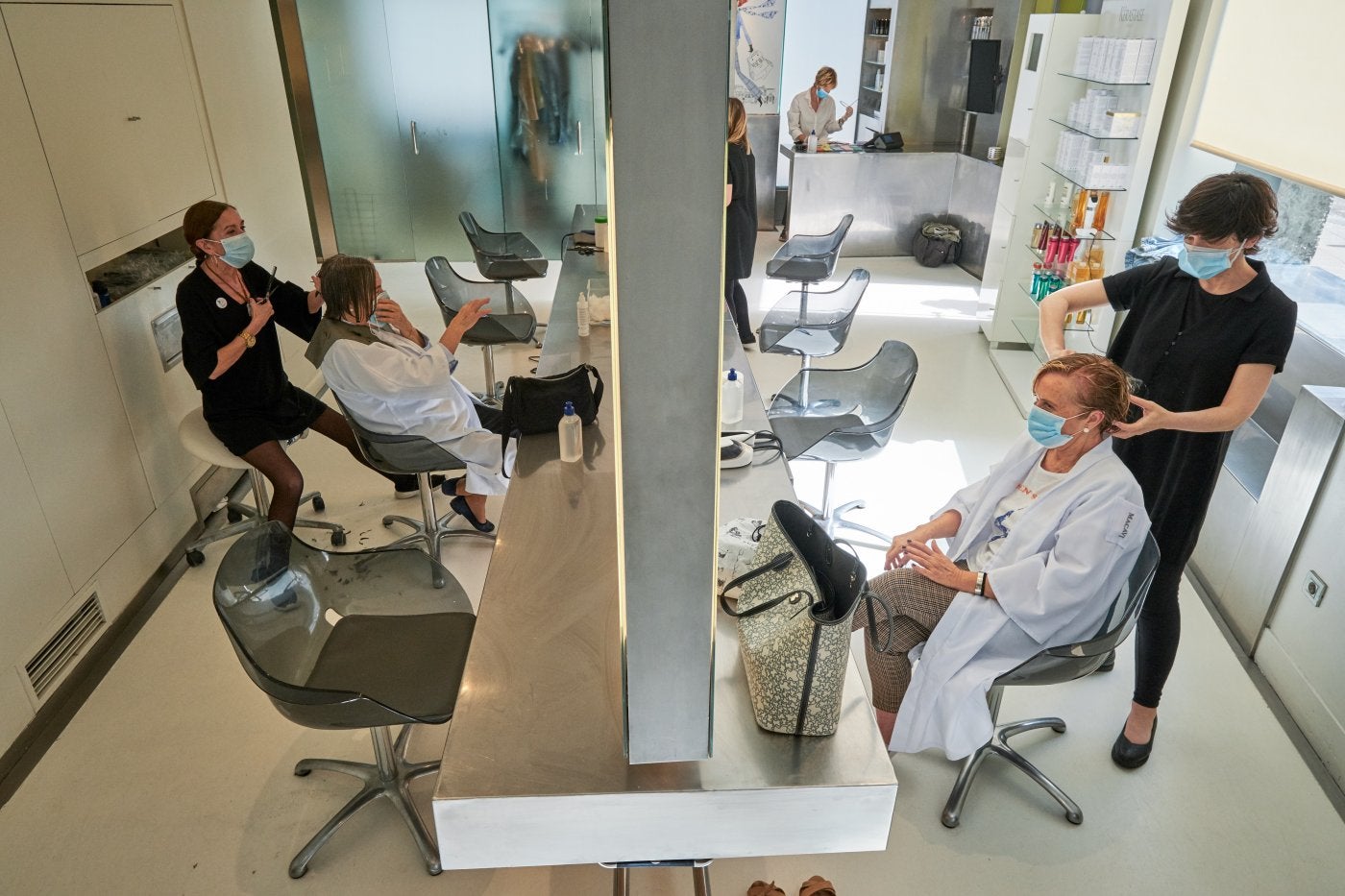 Una de las peluquerías Macavi, de Santander, ayer tras reabrir, atiende a varias clientas a la vez, manteniendo las distancias entre ellas.