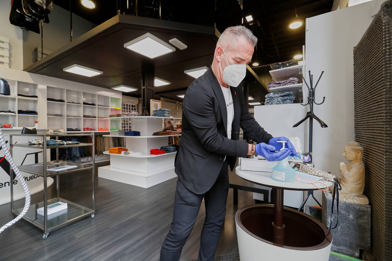 Imagen. Vicente Trueba se pone gel desinfectante de la mesita que ha puesto en la entrada de su tienda de moda.