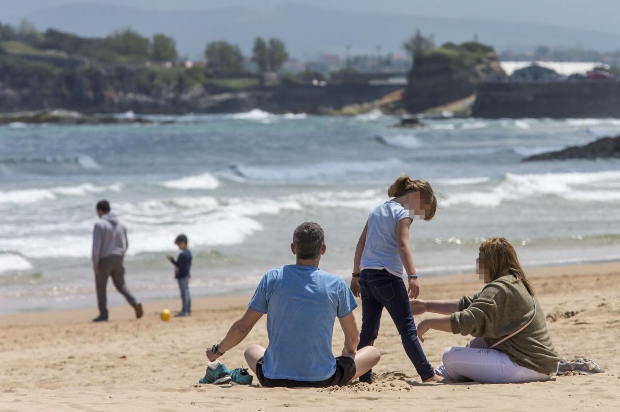 Una familia, sobre la arena de la playa de El Sardinero durante el primer fin de semana de la fase uno.