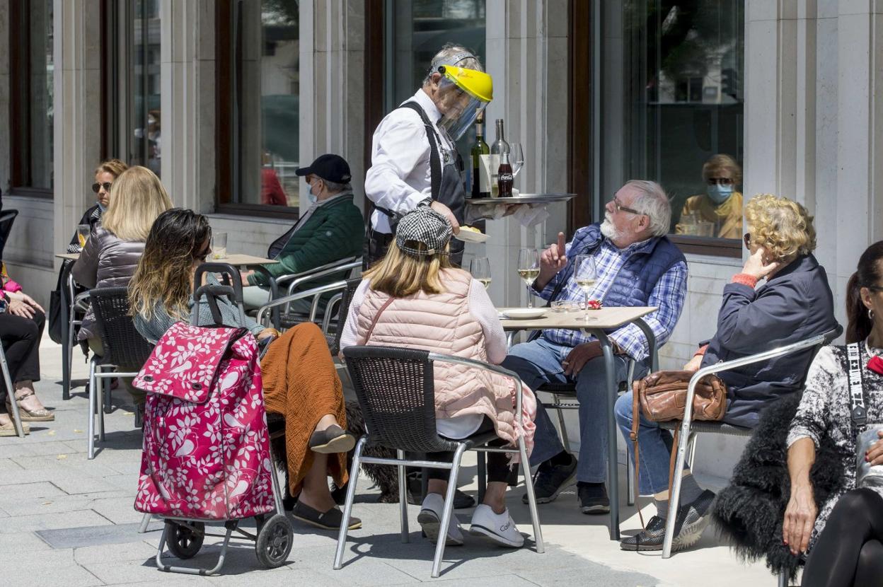 Un camarero atiende a unos clientes en una terraza de Santander en esta nueva coyuntura por el coronavirus. ROBERTO RUIZ