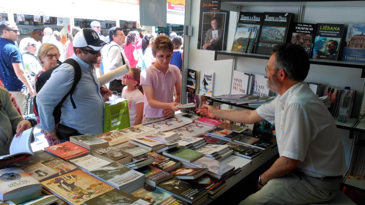 El escritor José Antonio Abella firma libros en el estand de Cantabria en la Feria de Madrid. 