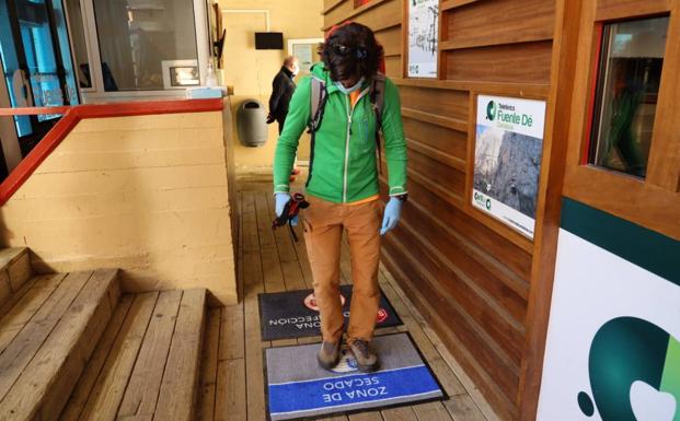 Un viajero se desinfecta los pies antes de subir a la cabina del teleférico.