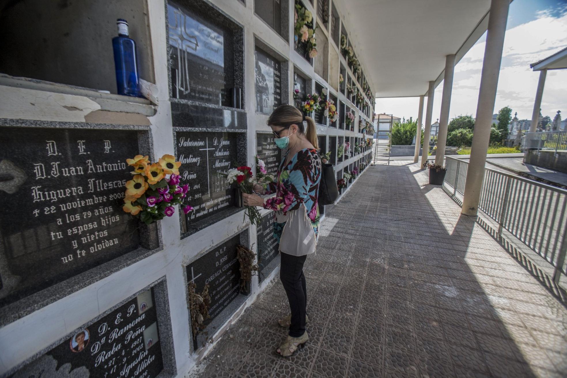 Una mujer deja flores a sus familiares difuntos. 