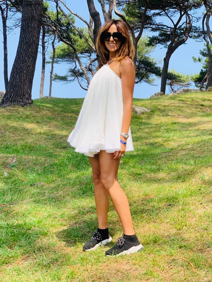 Look informal con vestido abullonado blanco atado al cuello y deportivas.