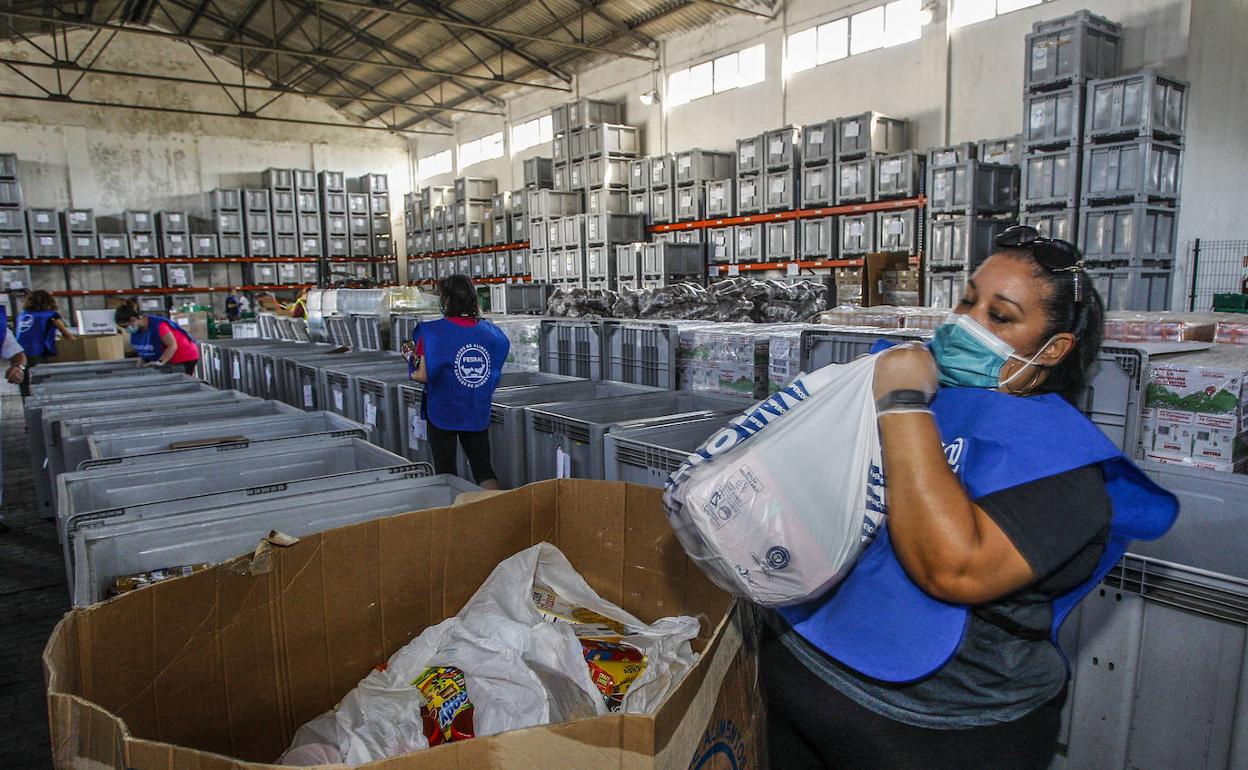 Una de las voluntarias del Banco de Alimentos coloca bolsas con lotes de comida sobre una caja.