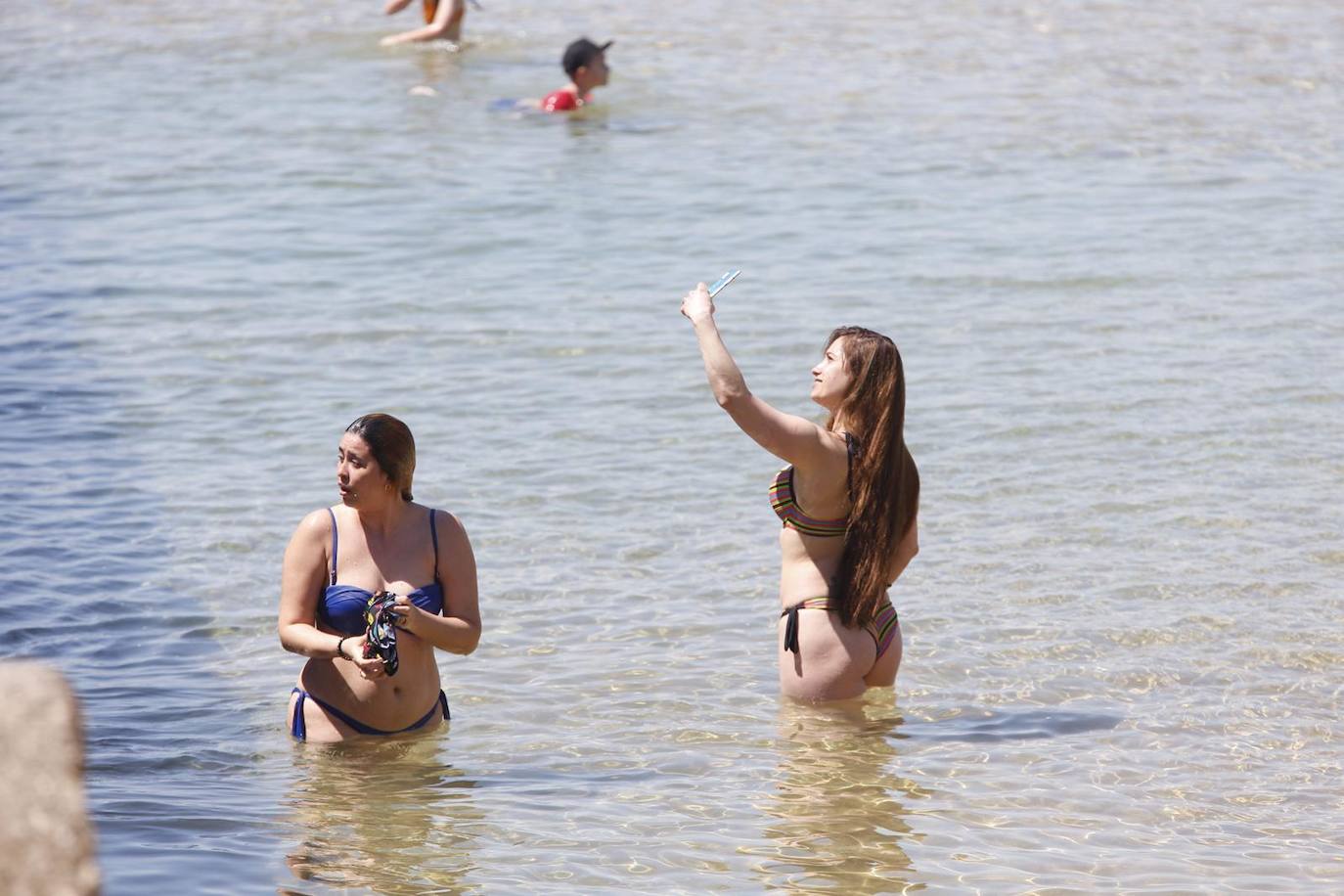 Aspecto que presentan este sábado las playas de El Sardinero y de la bahía de Santander, con muchos bañistas, gente paseando por la orilla, disfrutando del mar y tomando el sol.