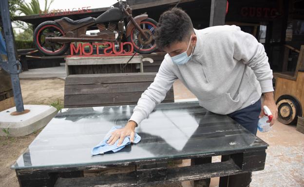 Enrique desinfecta una mesa de la terraza. 