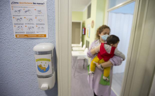 Imagen. Una educadora lleva a un niño de una sala a otra.