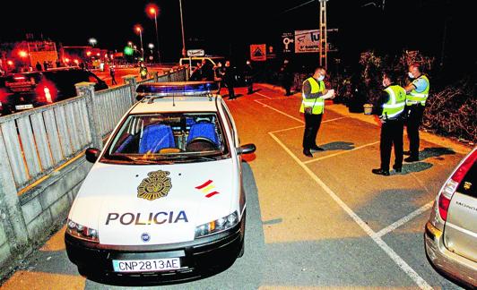 Agentes de la Policía recogen pistas en el aparcamiento del bar, con las vías a la derecha de la imagen. 