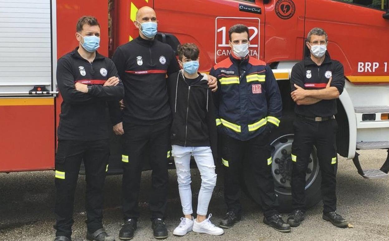 El joven rescatado, junto a cuatro bomberos en el parque de Valdáliga. 