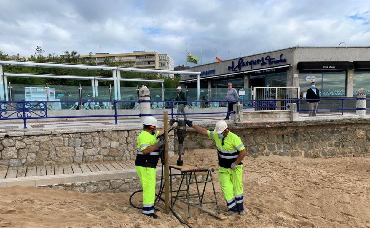 Operarios instalando los postes de madera hoy por la mañana en la Segunda de El Sardinero.