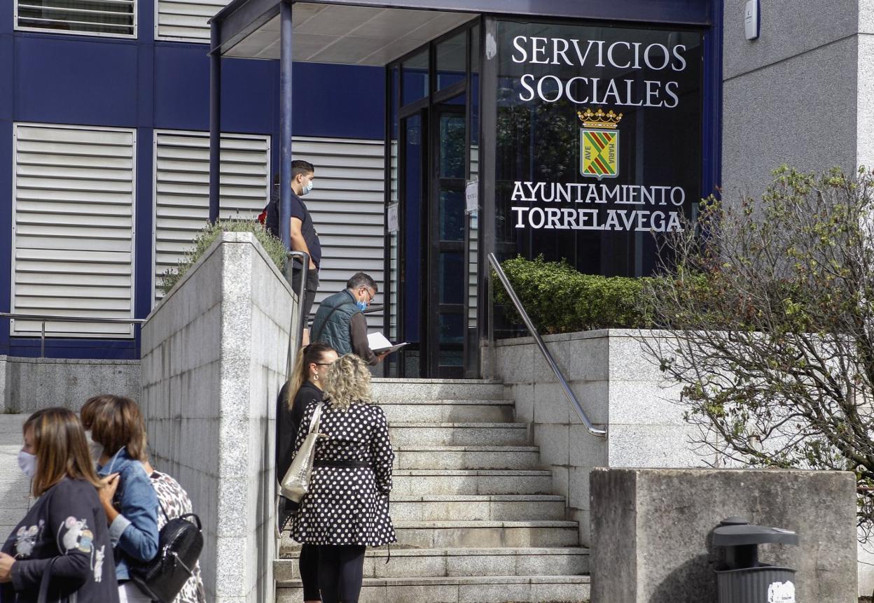 Los solicitantes hacen cola a la entrada de la sede de Servicios Sociales, en la avenida de España. 