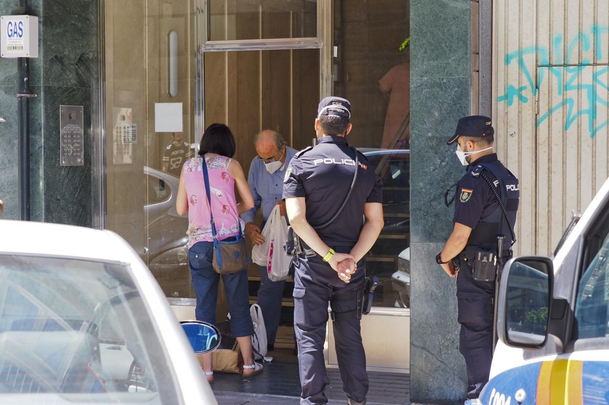 Un mujer deposita en el portal la compra hecha para un familiar del edificio afectado por el brote de coronavirus. 