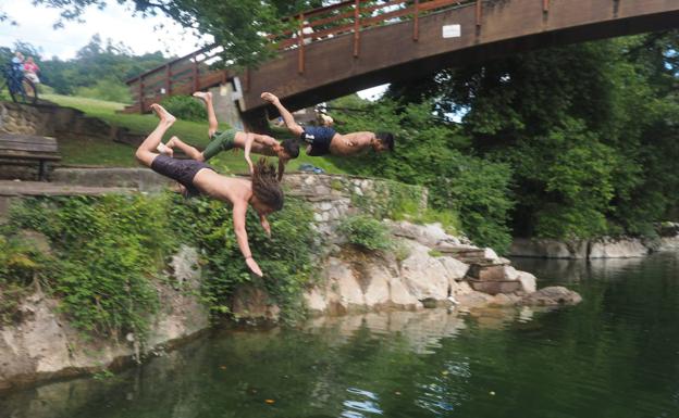 Tres bañistas se lanzan al río Pas en Puente Viesgo.