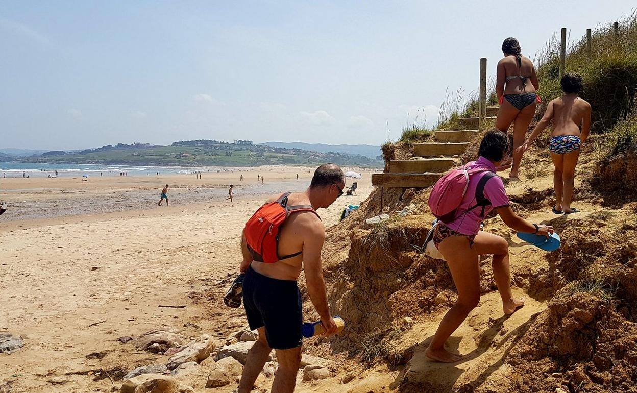 Una familia sale de la playa del Pájaro Amarillo por el acceso provisional que se encuentra en un pésimo estado. 