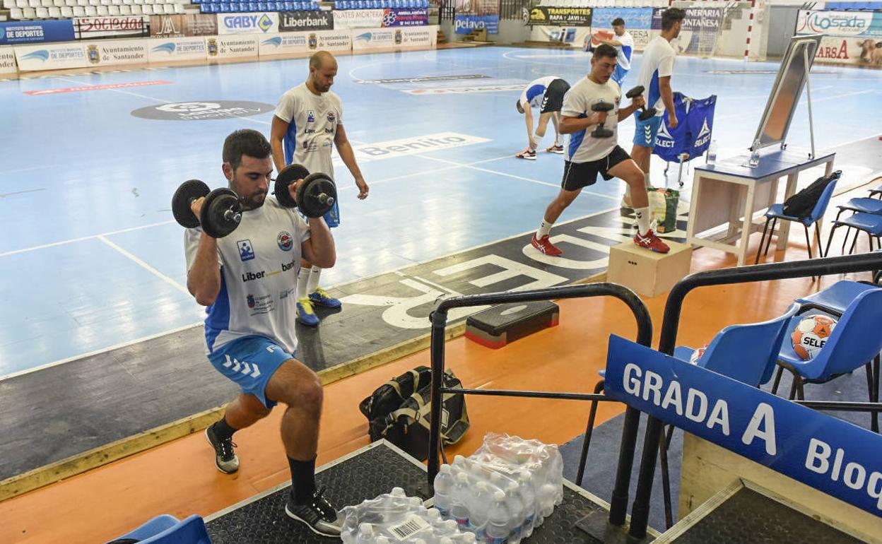 Álex Blázquez, en primer término, realiza ejercicios con mancuernas en el primer día de entrenamiento del Liberbank Cantabria.