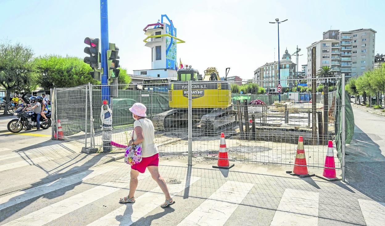 Una mujer pasea por delante de las obras del tanque de tormentas en El Sardinero. 