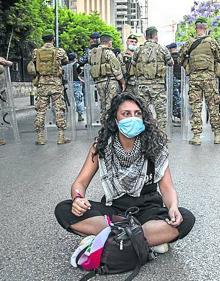 Imagen secundaria 2 - ARRIBA: Una mujer libanesa enseña su frigorífico vacío en Beirut. MEDIO: Una vista general de la acumulación de restos. ABAJO: Una joven ante policías antidisturbios